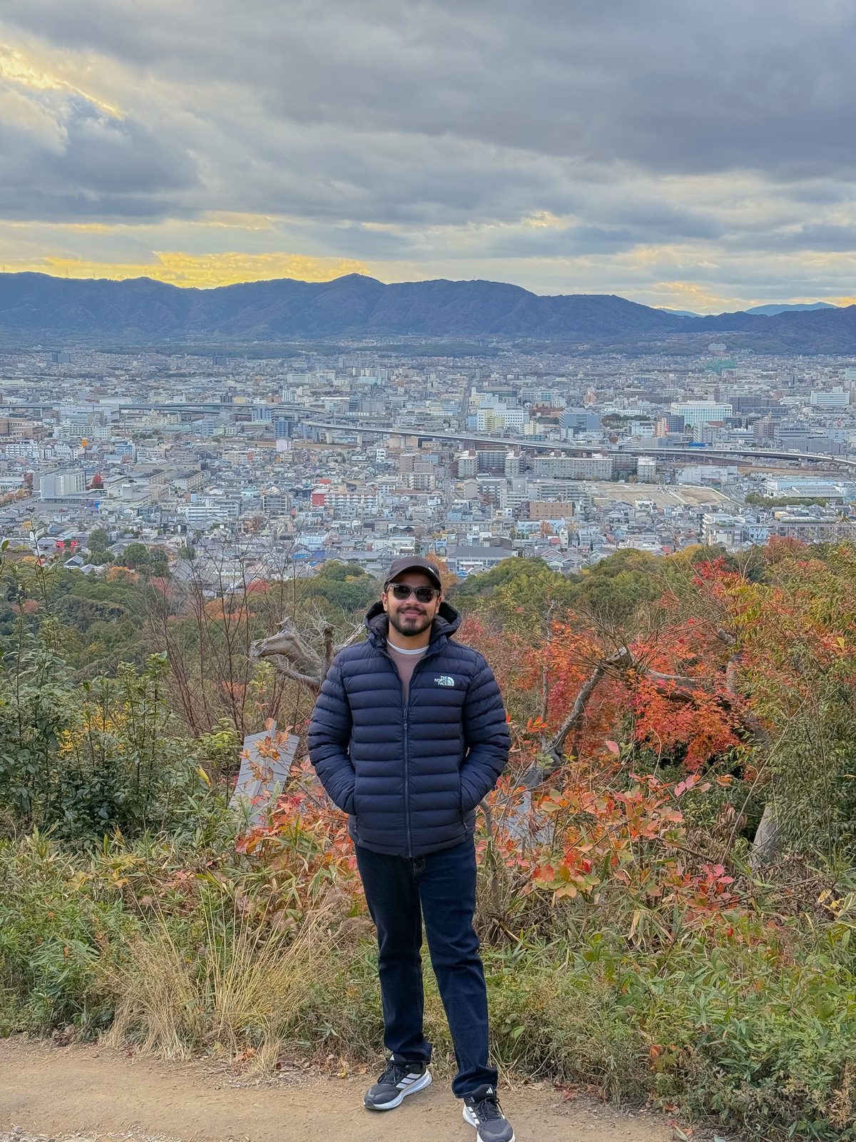 Faiq overlooking a Japanese city in autumn, mountains on the horizon