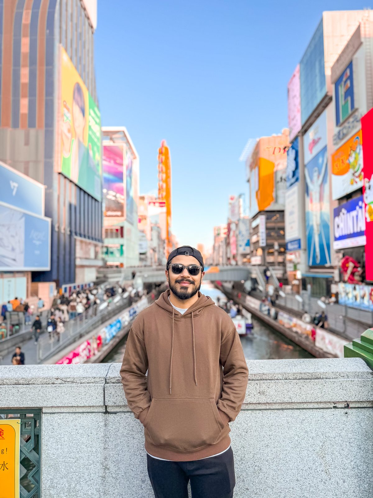 Faiq at Dotonbori canal in Osaka surrounded by giant billboards